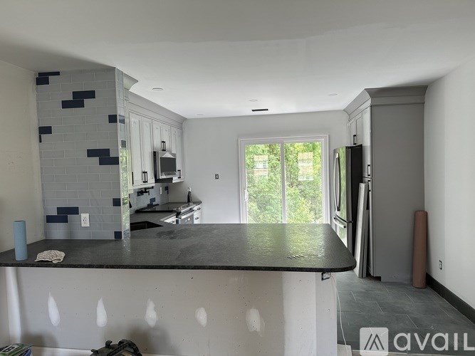 A kitchen with a black countertop and a blue tile backsplash.