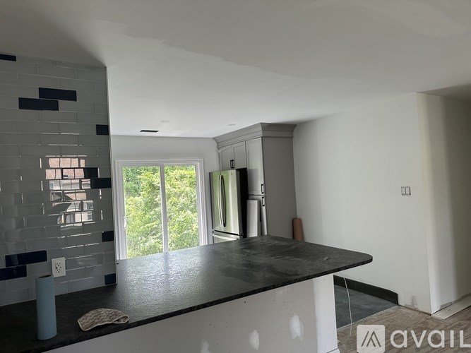 A kitchen with a black countertop and a tiled backsplash.