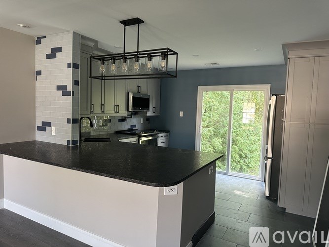 A modern kitchen with a black countertop and white cabinets.