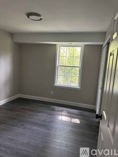 A room with a window and wooden flooring.