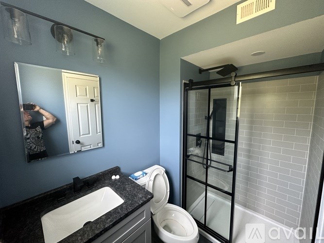 A person is taking a picture of a bathroom with blue walls.