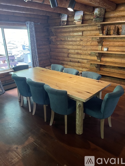 A wooden table surrounded by blue chairs in a room with a wooden wall.