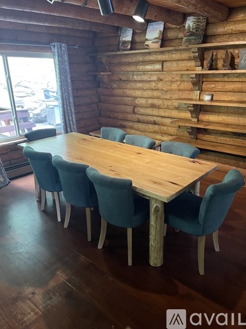 A wooden table surrounded by blue chairs in a room with a wooden wall.