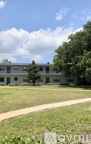 A building with a white fence and a tree in front of it.