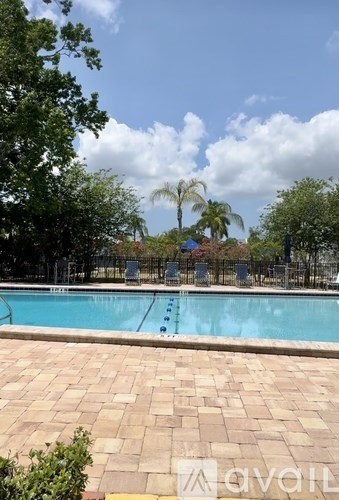 A pool surrounded by trees and a brick patio.