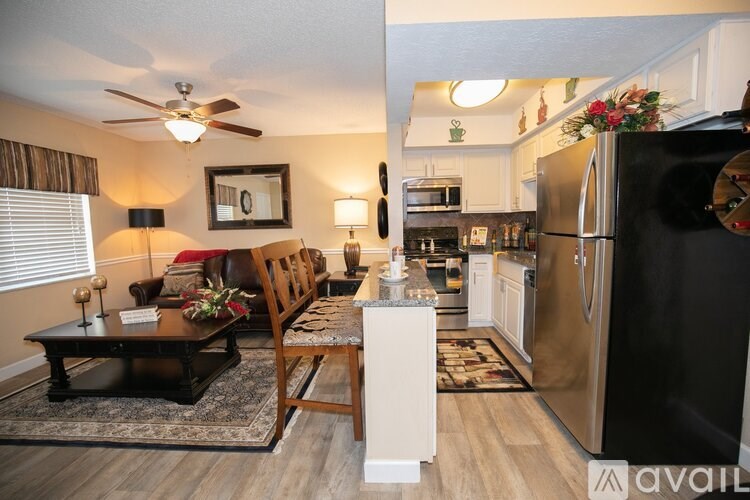 A kitchen with a black fridge and a wooden table with a vase of flowers on it.