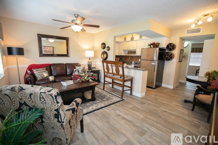 A living room with a couch, chair, and a dining area in the background.