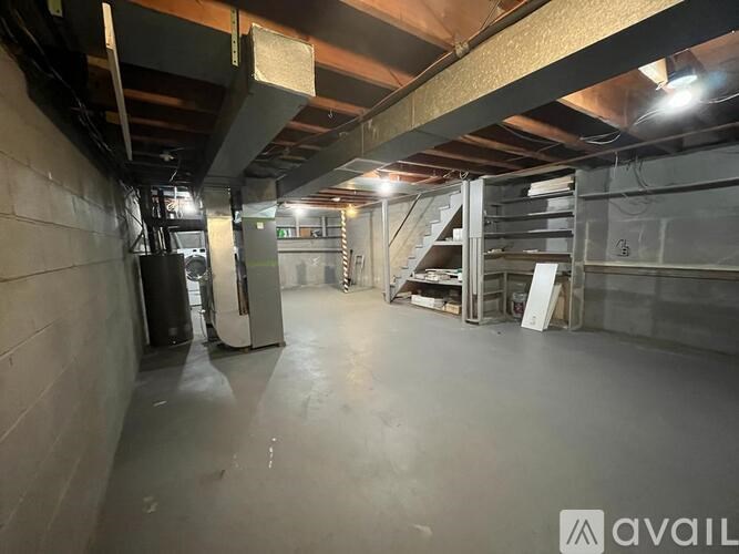 A spacious, empty basement with concrete walls and floors, and a metal staircase in the background.