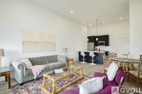 A living room with a grey sofa, a coffee table, and a dining table set up.