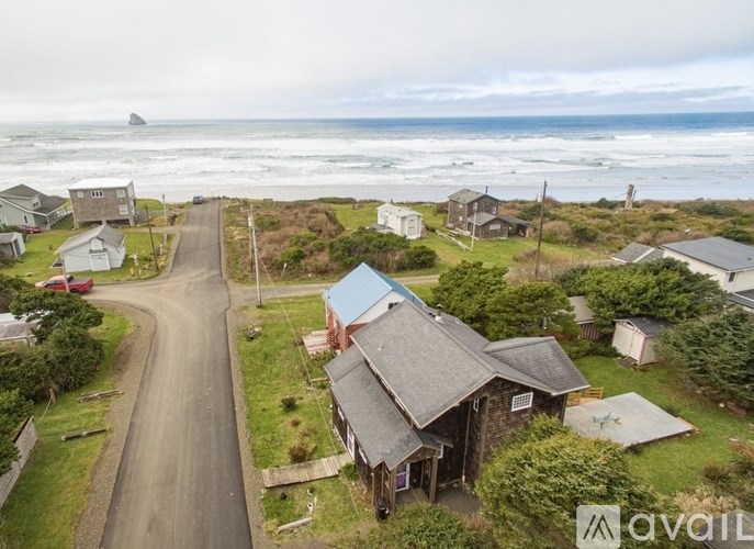 A house with a grey roof is situated on a road with a view of the ocean.
