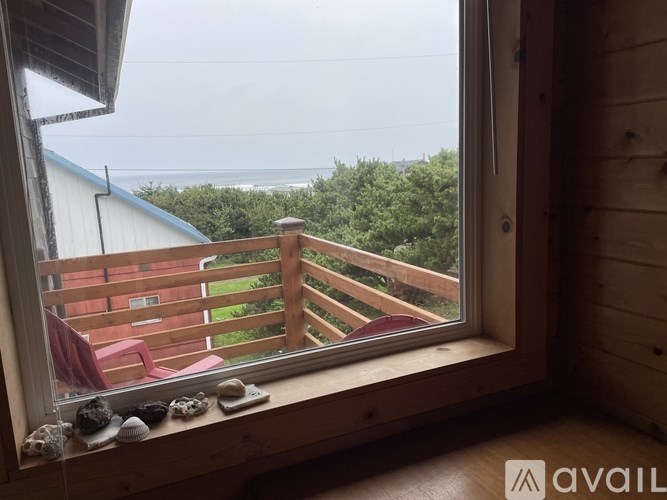 A window with a view of a balcony and trees.
