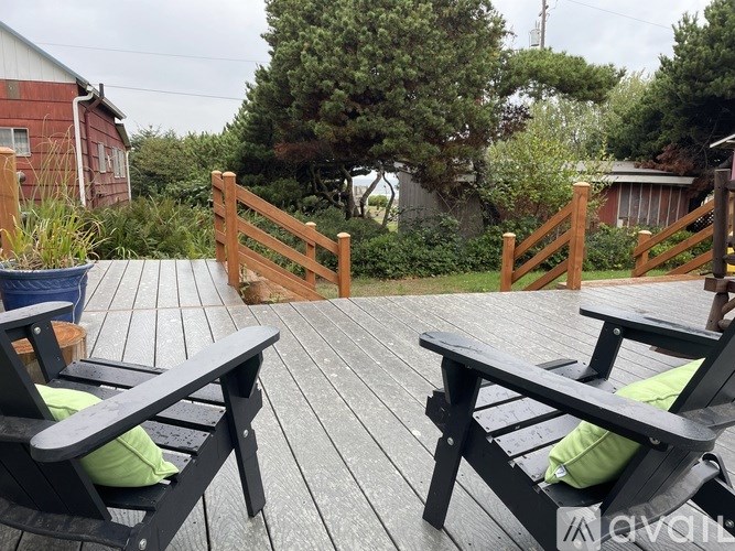 Two wooden chairs with green cushions are on a wooden deck.