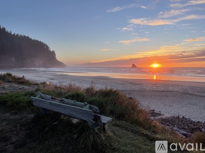 A bench overlooks a beach at sunset.
