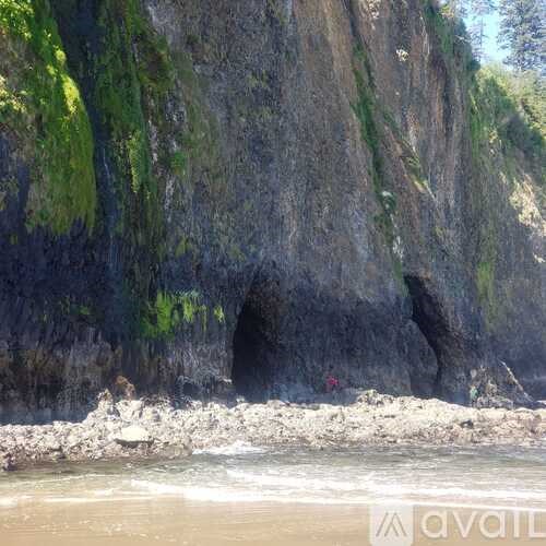 A rocky beach with a large rock formation and a cave entrance.