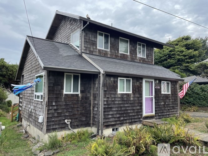 A wooden house with a purple door and an American flag.