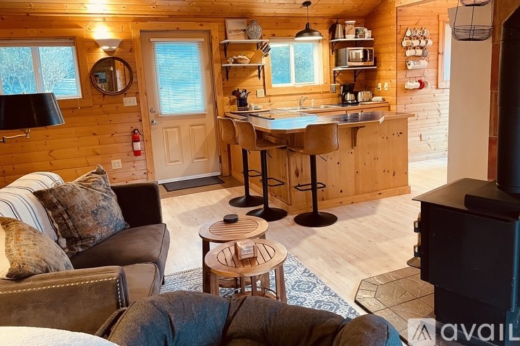 A cozy living room with a fireplace and a kitchen area in the background.