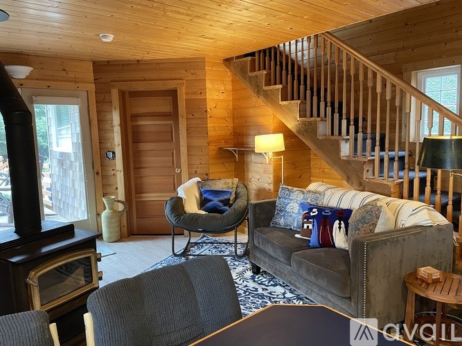 A living room with a grey couch and a wooden staircase.