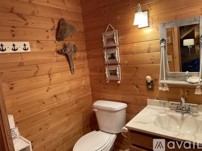 A wooden bathroom with a toilet, sink, and mirror.