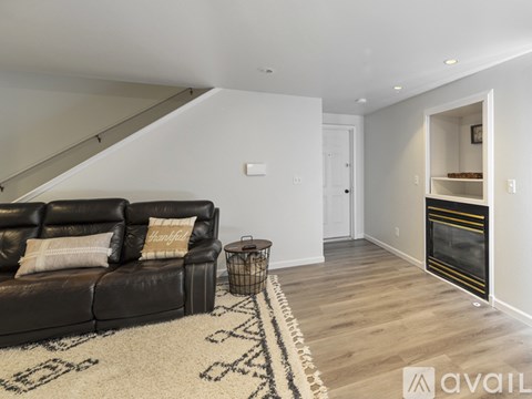A living room with a black couch and a rug with letters on it.