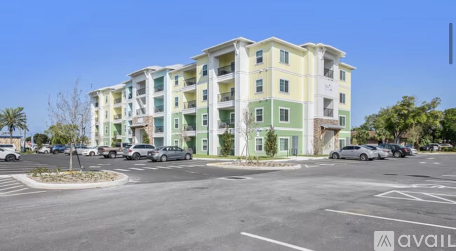 A parking lot in front of a multi-story building with cars parked.