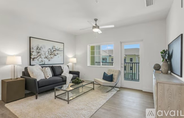 A living room with a grey couch, a glass coffee table, and a flat screen TV mounted on the wall.