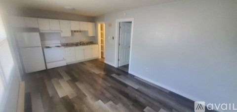 A kitchen with white cabinets and a wooden floor.