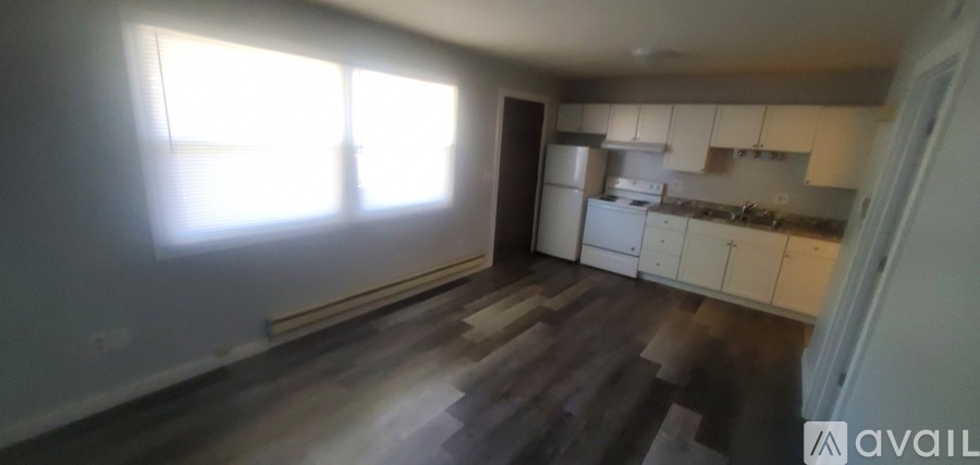 A kitchen with white cabinets and a window letting in sunlight.
