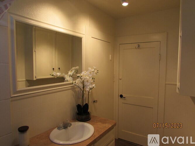 A bathroom with a sink, mirror, and flowers.