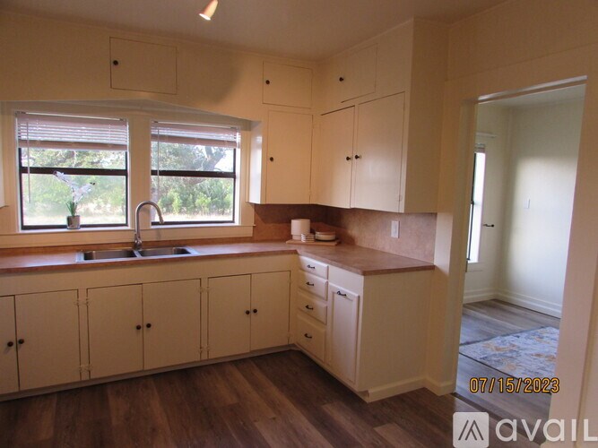 A kitchen with wooden cabinets and a window overlooking a garden.