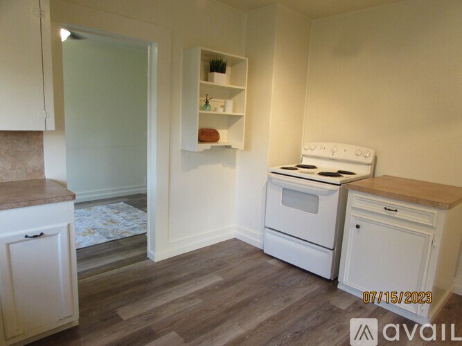 A kitchen with white appliances and wooden floors.