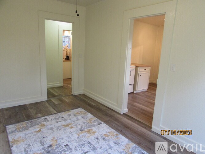 A room with a rug on the floor and a fridge in the corner.