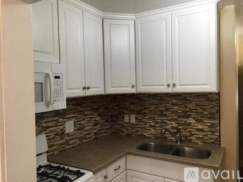 A kitchen with white cabinets and a stone backsplash.