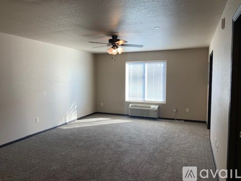 A room with a ceiling fan and a window with blinds.
