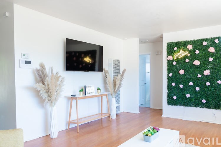 A living room with a flat screen TV mounted on the wall and a green wall hanging.