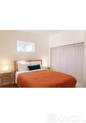 A bedroom with a bed, nightstand, and window.