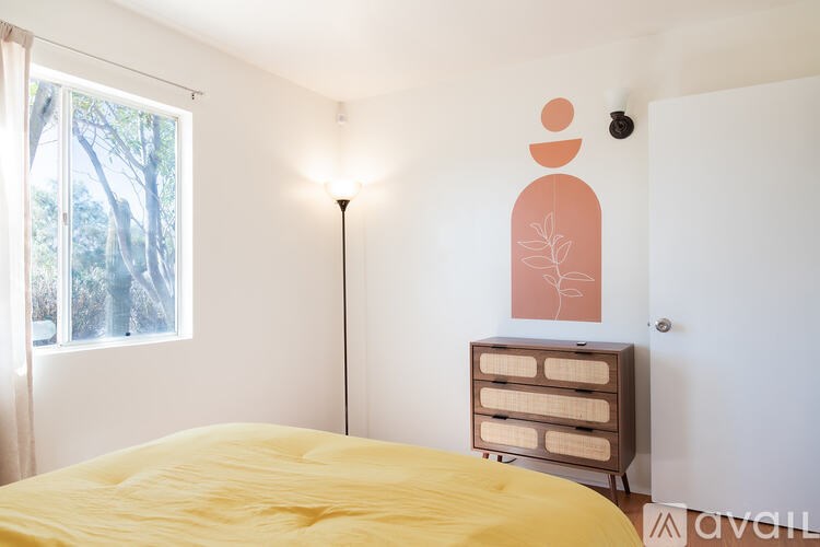 A bedroom with a bed, dresser, and a window.