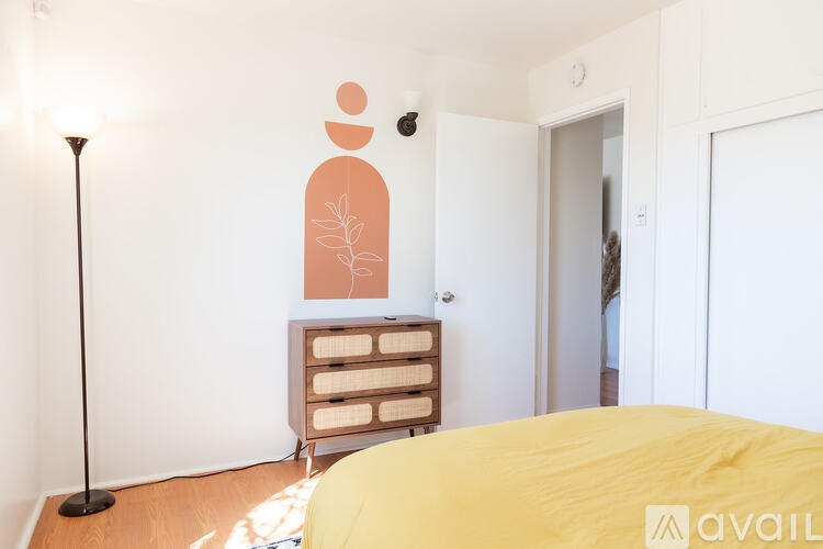 A bedroom with a bed, dresser, and lamp.