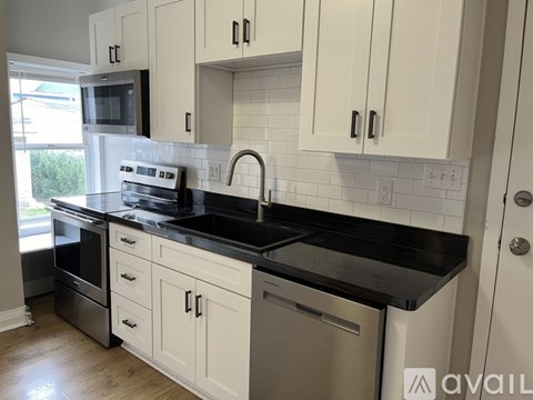 A kitchen with white cabinets and black countertops.