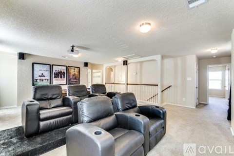 A living room with black leather couches and a carpet.