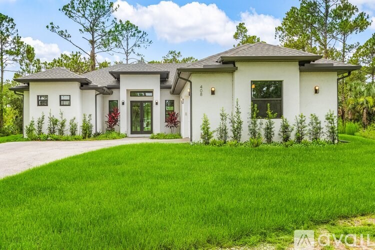 A white house with a grey roof and a green lawn in front.