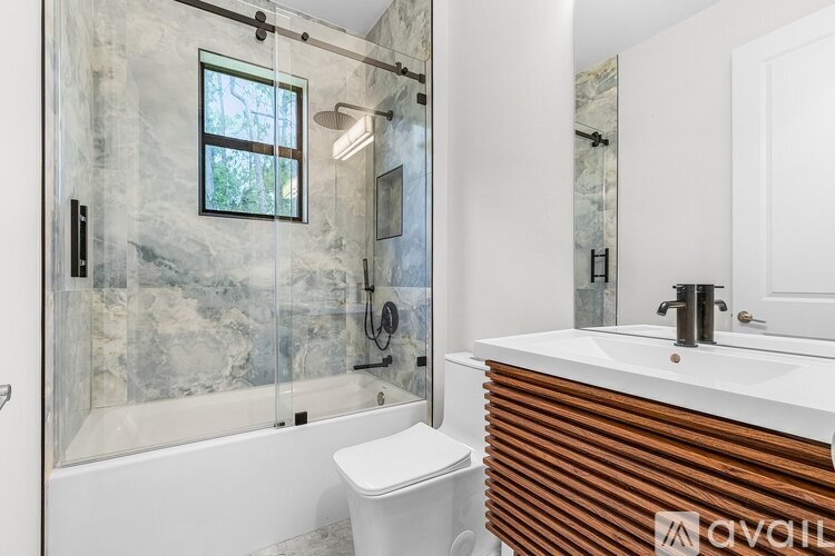 A bathroom with a marble wall and a white toilet.