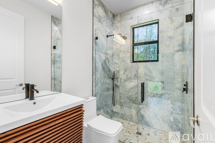 A bathroom with a marble wall and a window in the shower.