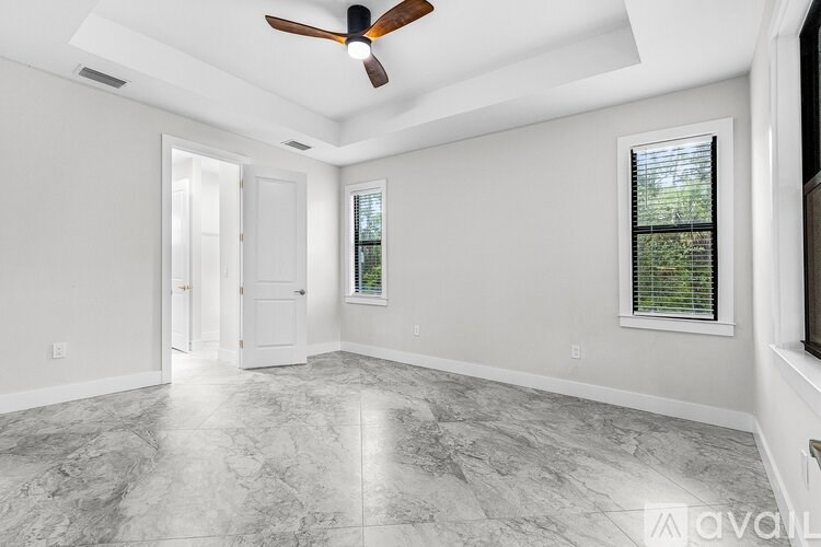 A spacious room with a ceiling fan and marble flooring.