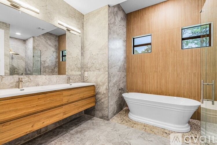 A modern bathroom with a white bathtub and wooden vanity.