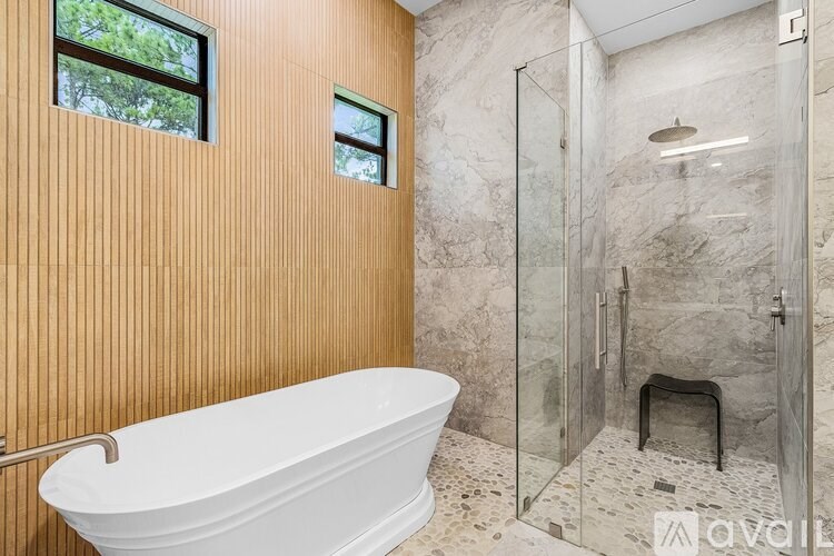 A bathroom with a white bathtub and a glass shower stall.