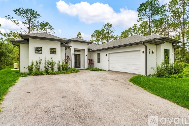 A house with a white garage door is surrounded by greenery.