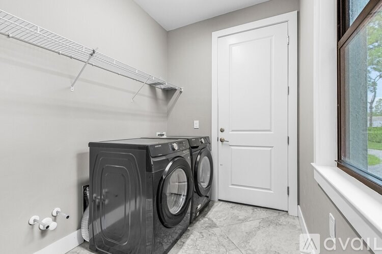 A black washing machine and dryer in a laundry room.