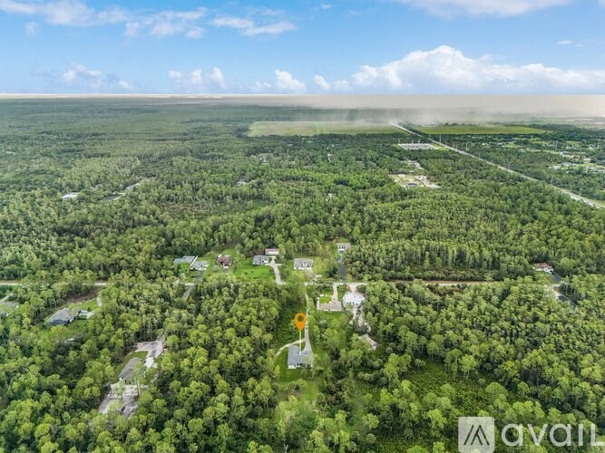 An aerial view of a forested area with a small cluster of buildings in the center.