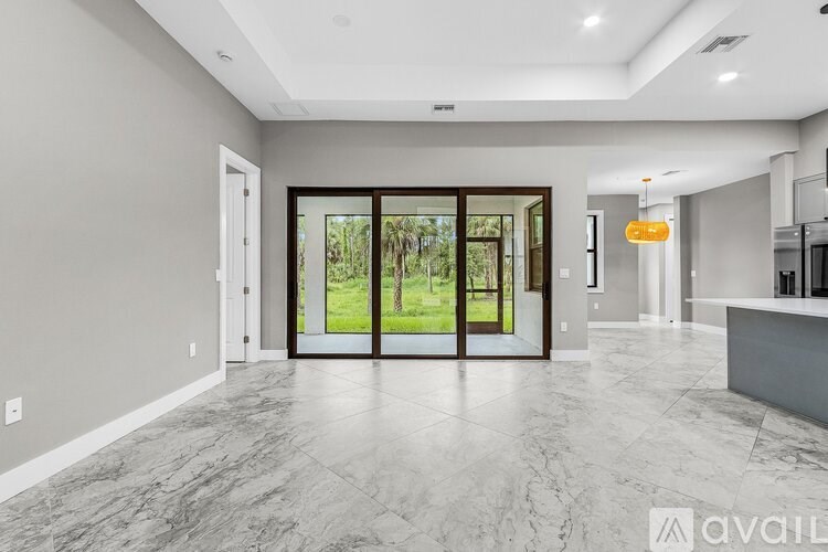A spacious, well-lit room with marble flooring and a view of greenery through the glass doors.