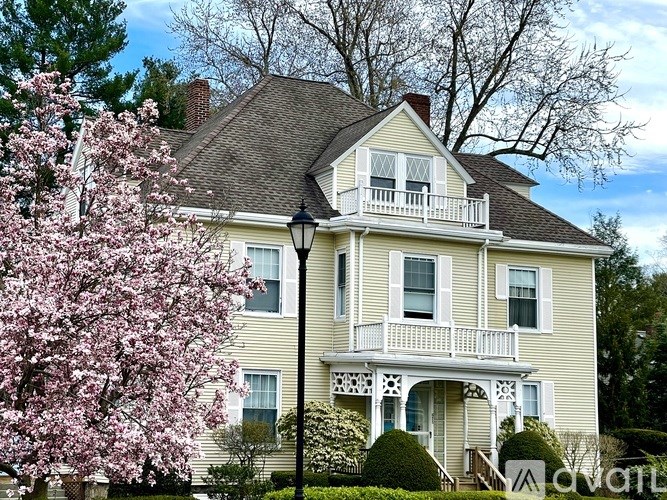 A yellow house with a balcony and a lamp post in front.